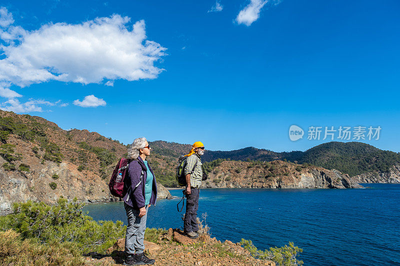 一对上了年纪的徒步旅行者在欣赏风景，欣赏他们周围的环境