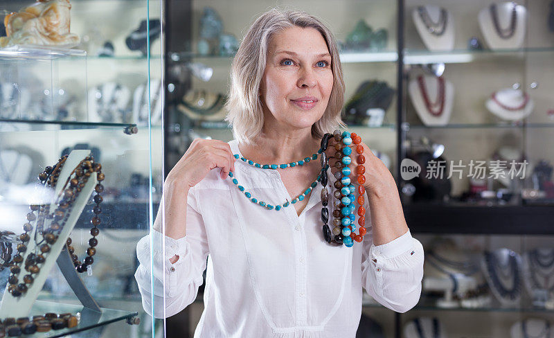 一名成年女子从商店里的绿松石首饰中挑选珠宝