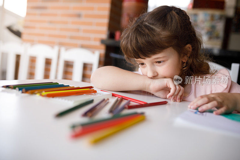 女孩看着彩色铅笔选择哪一个使用