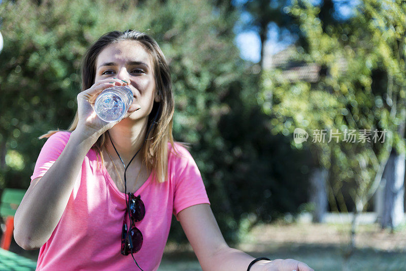 一个年轻女子在公园里一边听音乐一边用手机冲浪