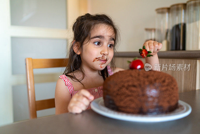 小女孩的幸福，因为她开始吃一个巨大的巧克力蛋糕