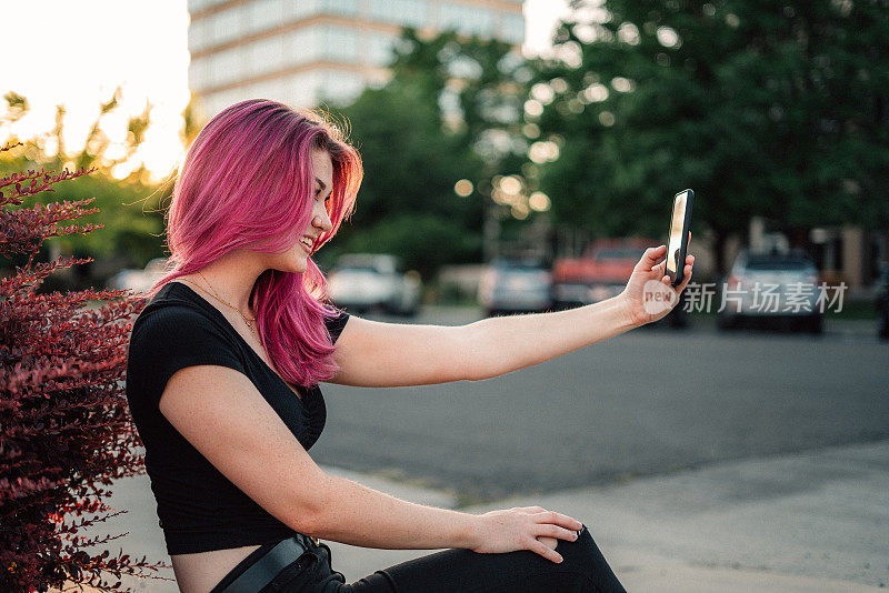 一个时尚的年轻女人的肖像与有趣的粉红色头发在户外在夏天自拍