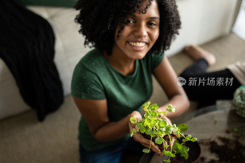 一个十几岁的女孩在家里抱着一株植物的肖像