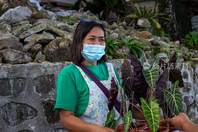 戴着面具卖花的女人。友好的菲律宾防毒面具上市了。