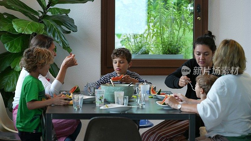 一家人聚在桌子上吃着食物，真实的一家人在午餐时间坐着