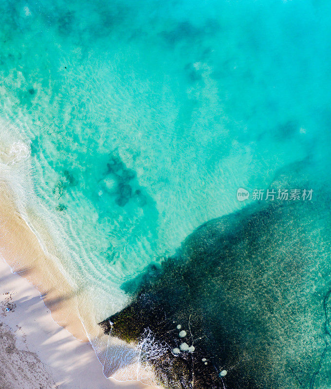 从上面的海滩场景——蓝色的海浪拍打着沙滩。