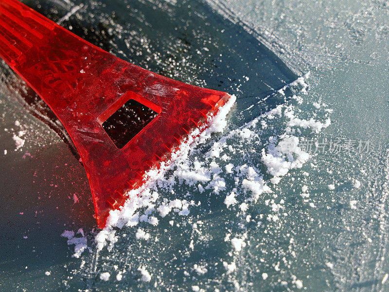红色刮刀清除汽车挡风玻璃上的冰，关闭
