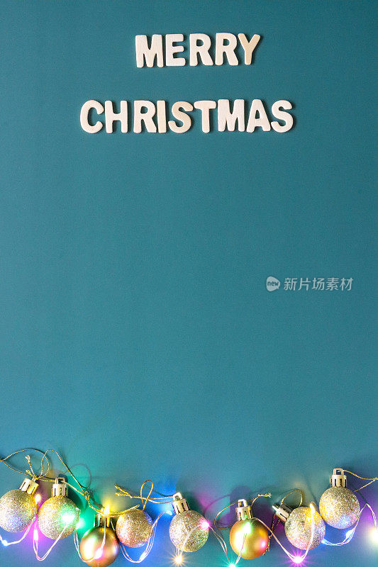 自制DIY简单的圣诞卡设计的图像，在蓝绿色的背景上剪出白色字母，手工制作的节日圣诞贺卡，圣诞快乐的信息与金色的小玩意和发光的仙女灯，复制空间