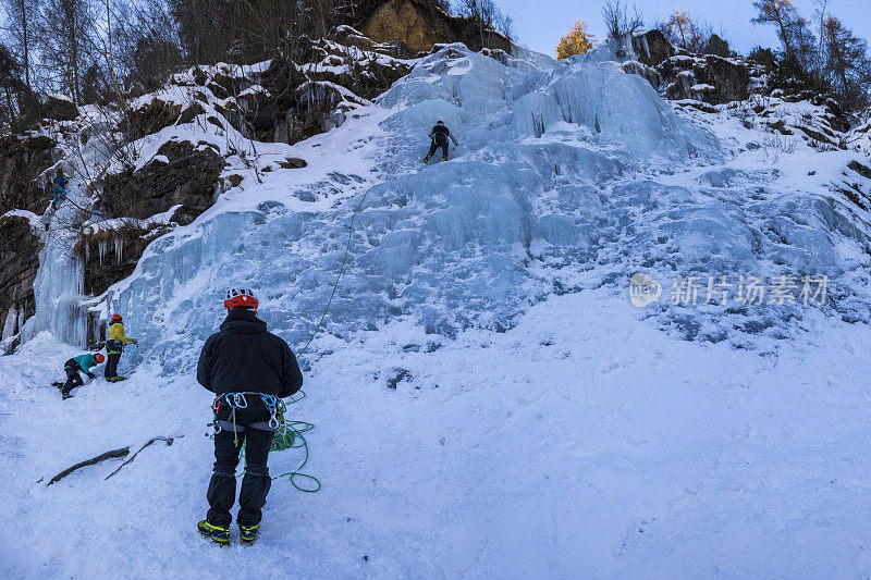 攀冰者在攀爬冰冻瀑布时保护其他攀冰者