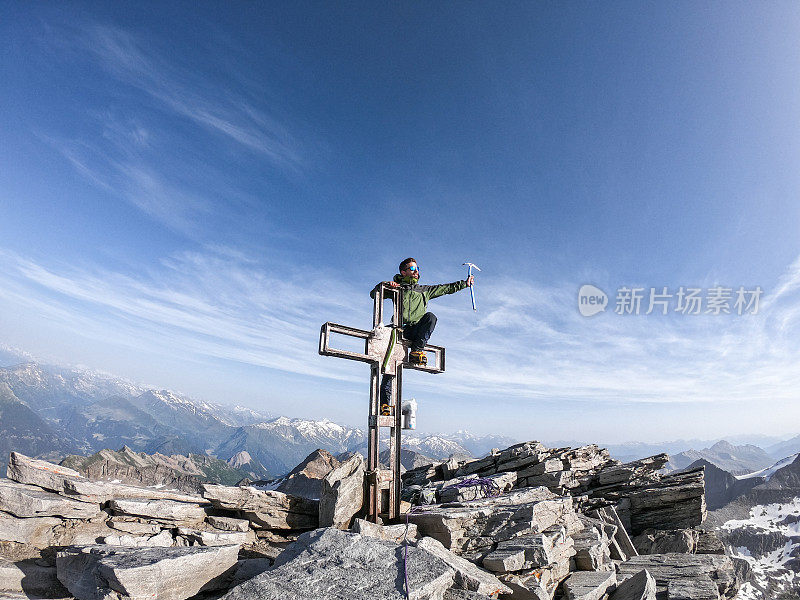 登山者坐在山顶的十字架上凝视着山顶的景色