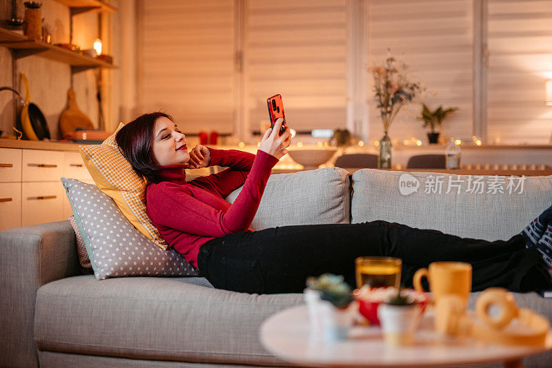 一个女人在沙发上放松，一边打电话一边发短信