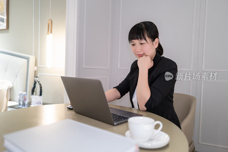 一位女士一边喝咖啡一边在电脑前工作