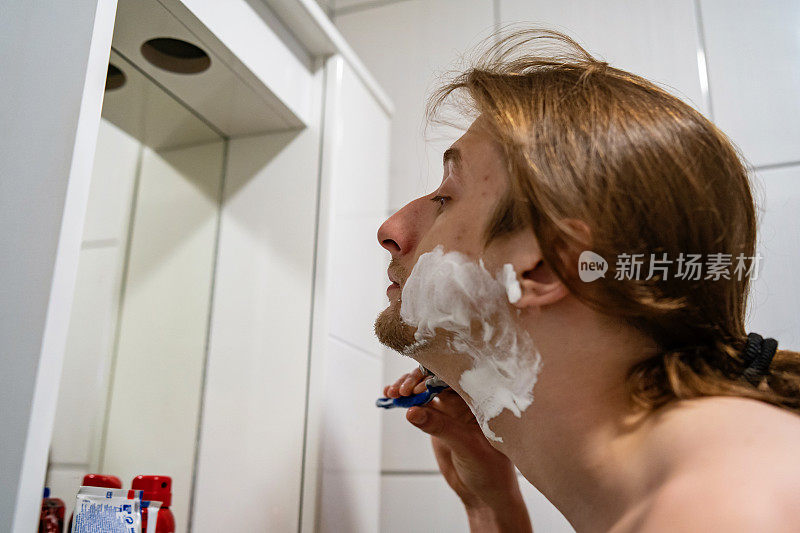 年轻男子在浴室刮胡子