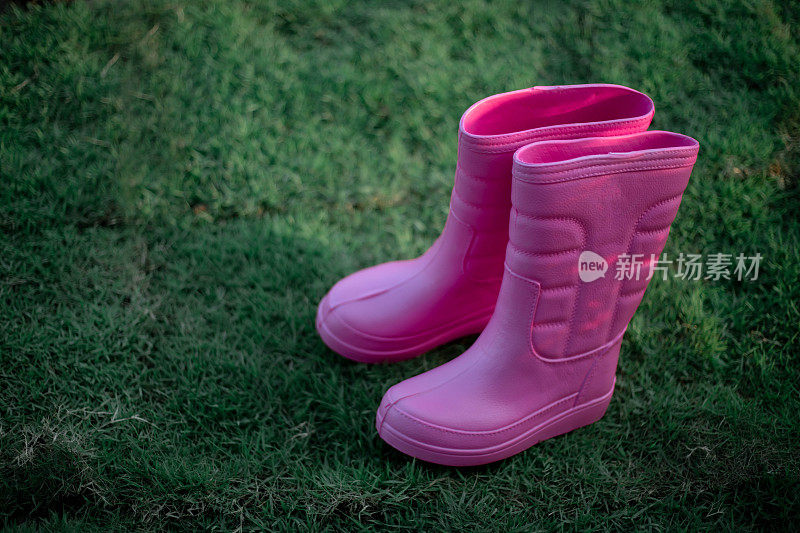 绿色草坪上的粉色胶靴