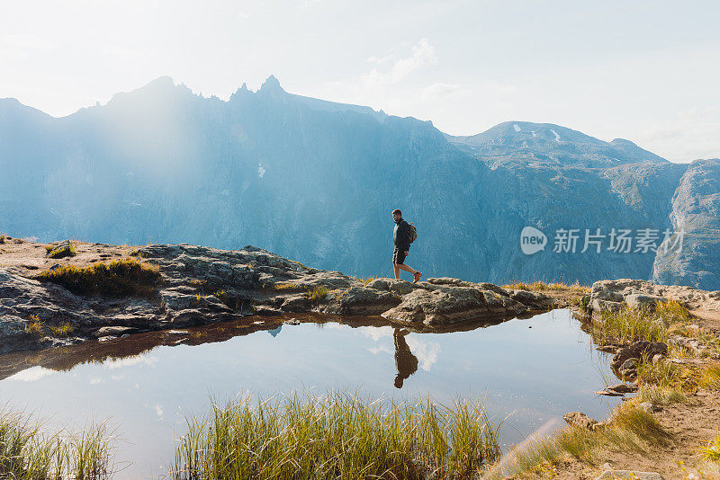 在阳光明媚的秋日，一个背着背包的人在挪威的山上徒步旅行