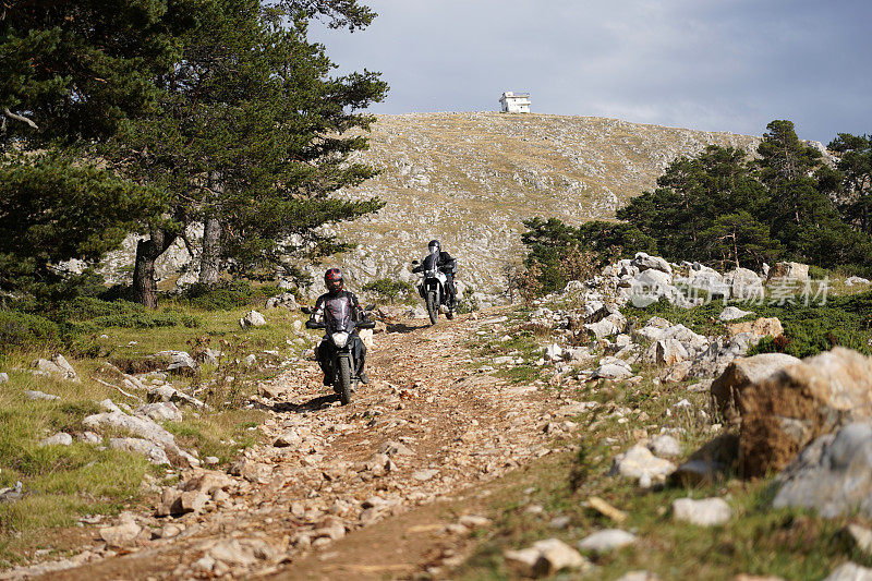 两名男子在山路上骑越野摩托车