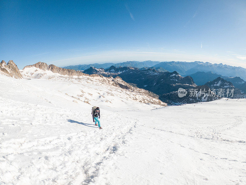 女登山者在雪道上攀登山峰