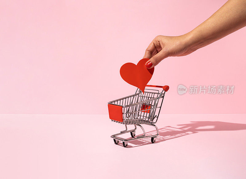 女性将红纸心放入购物车。最小限度的爱或情人节的概念。