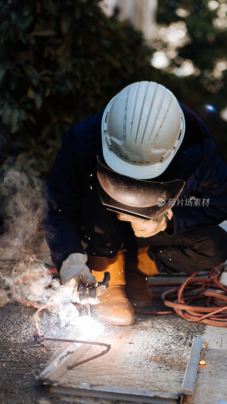 一名中年男性工人正在使用切割机和焊机