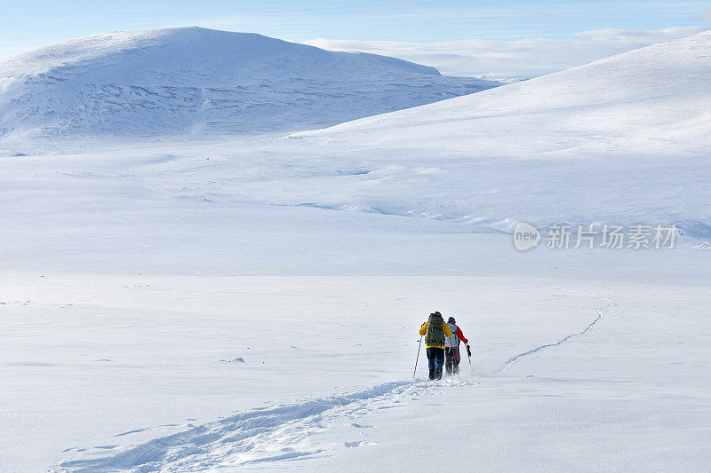 在一个阳光明媚的日子里，穿着雪鞋的徒步旅行者在Dovrefjell山徒步
