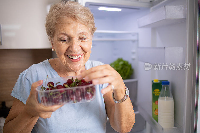 老妇人正在从冰箱里拿食物