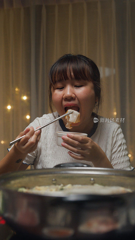晚上，一群快乐的亚洲朋友在家里吃着火锅，聚在一起吃春节团圆饭。生活方式享受美食。垂直的屏幕。
