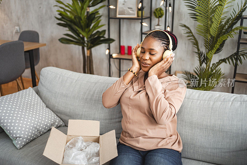 一名黑人妇女正在试用刚送到她家的新无线耳机