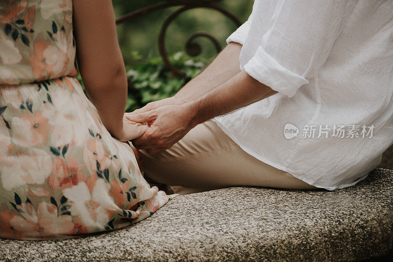 夏天，可爱的情侣手牵着手坐在石凳上