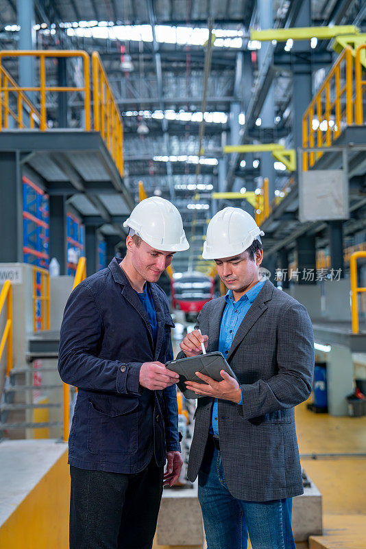 职业经理或工程师工人在工厂电气或地铁列车前与平板电脑一起讨论的垂直图像。