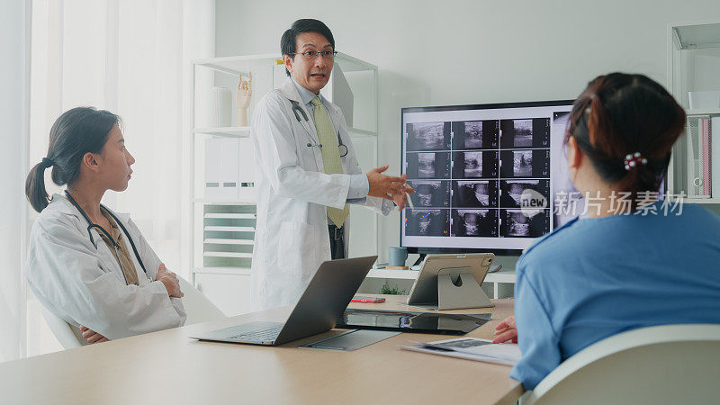 医疗队亚洲男、女医生在医院电脑上检查病人的x线图像，讨论结果。医疗保健。