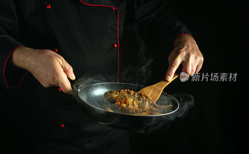 厨师在餐厅的厨房里准备河鱼。在煎锅中煎鲫鱼。美味的鱼肉食谱