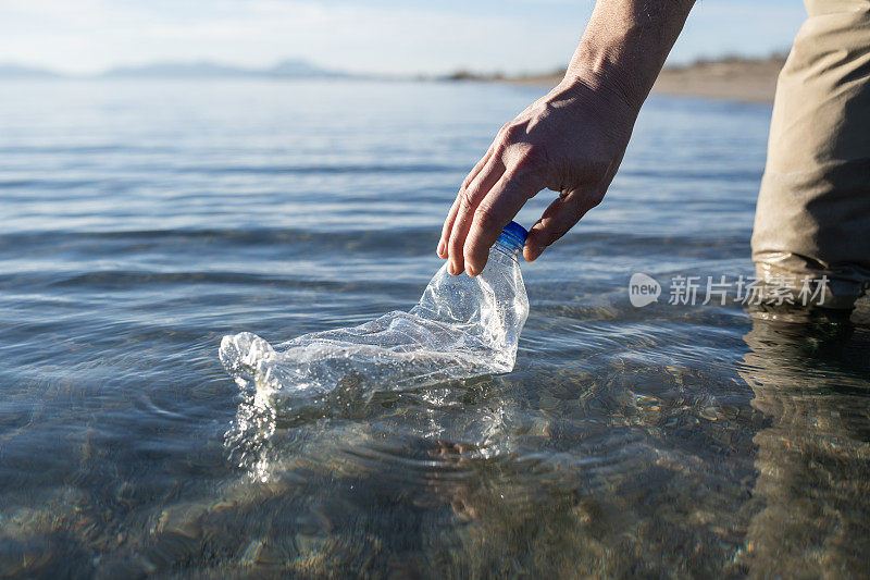 一个无法辨认的人在清理海洋中的塑料瓶。