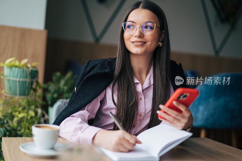 年轻的女商人边打电话边写便条