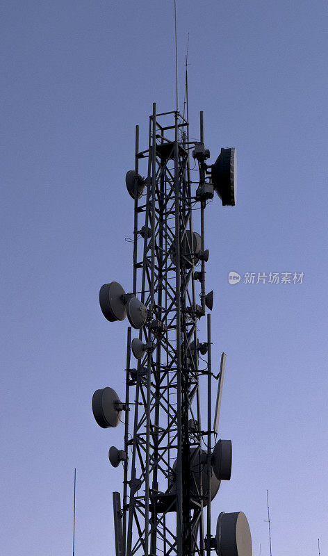 在落日的天空中，一座金属通讯塔巍然耸立。