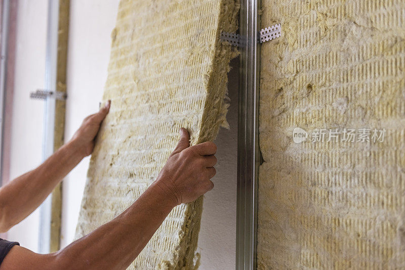 工人用矿物岩棉保温材料保温房间墙壁。