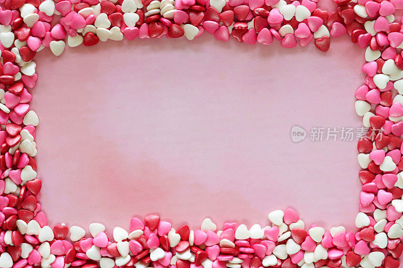 形象情人节设计海报框架由红色、粉色和白色心形糖果打造，情人节装饰，斑驳的粉色背景，抬高视野，情人节和浪漫的概念，复制空间