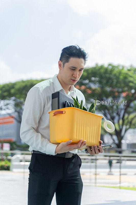 一名中国男子在被裁员后拿着自己的行李