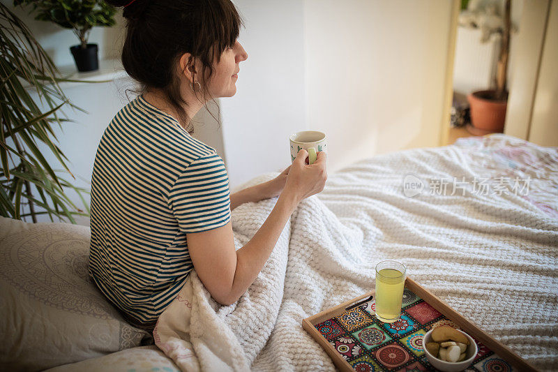 年轻女子在享受她的第一杯清晨咖啡。