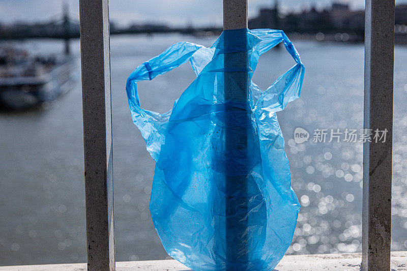 布达佩斯多瑙河上的伊丽莎白桥栏杆上挂着一个蓝色塑料袋。城市里的垃圾。环境污染概念。生态灾难，灾难。有选择性的重点
