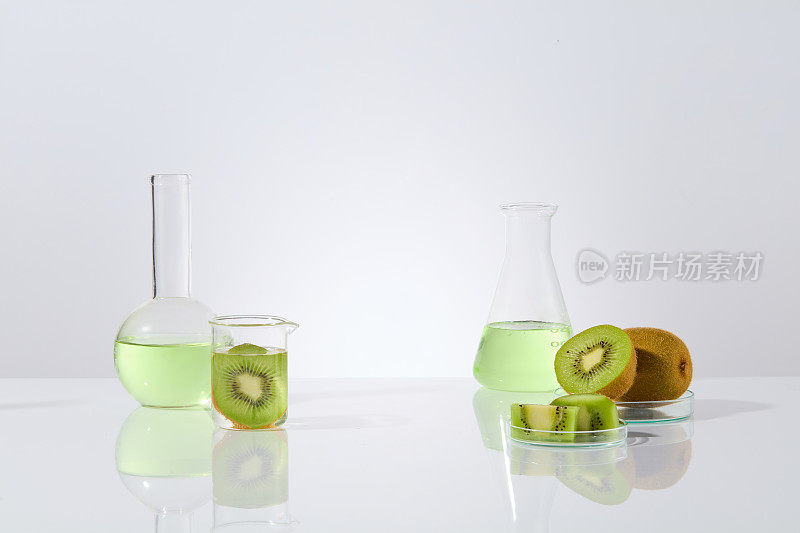 各种类型的实验室玻璃器皿具有白色背景与猕猴桃成分，照片为广告保健或美容护理产品从猕猴桃提取。前视图，为文本留出空间