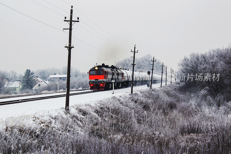 一列明亮的橙色货运火车在冬天行驶。