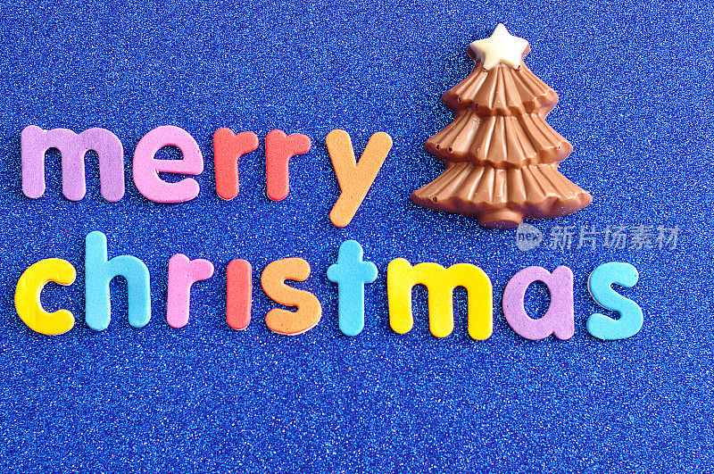 一棵蓝色背景上写着“圣诞快乐”的巧克力圣诞树