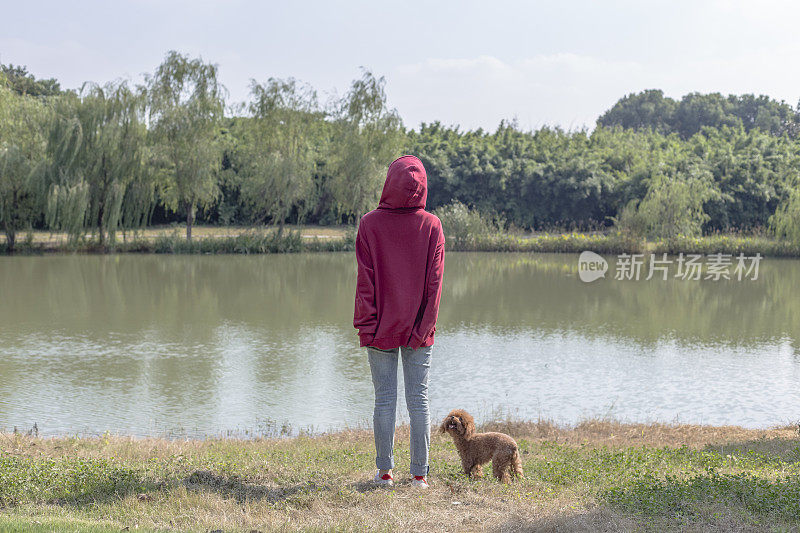 一个女人和她的小狗在湖边玩耍