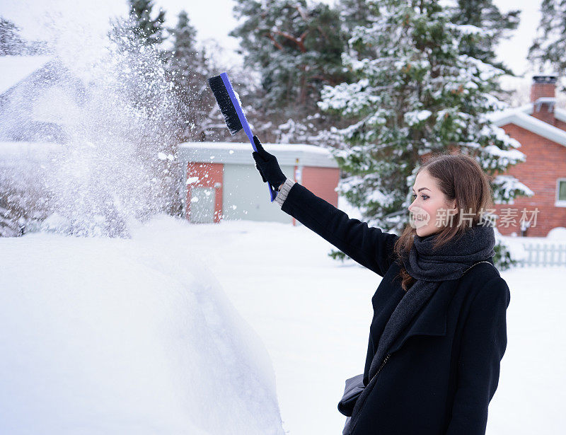 冬天即将来临。女人在冰冷的天气里，车被雪覆盖着。