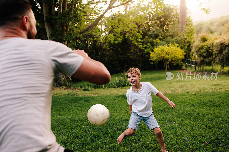 父亲和儿子在后院的花园里踢足球