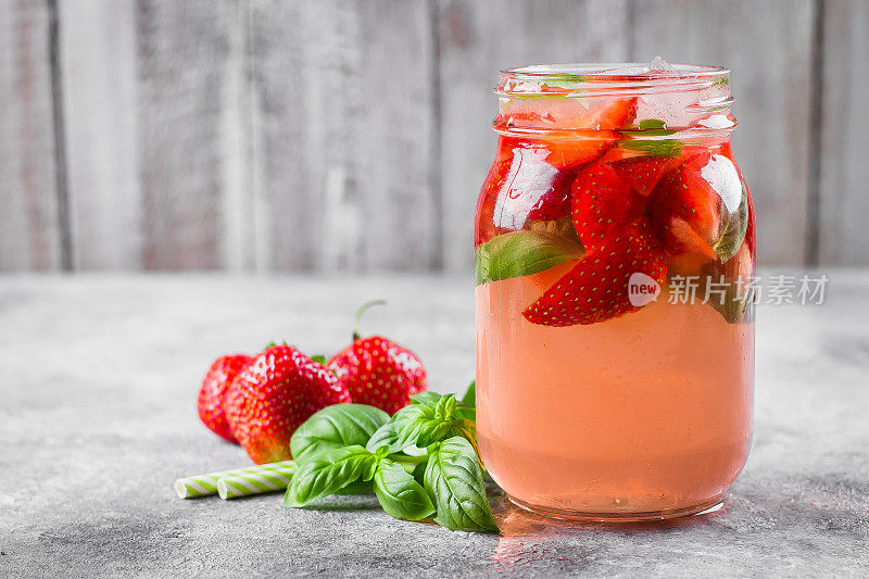 夏季食物和饮料。水泥桌上放着一瓶草莓罗勒柠檬水。本空间