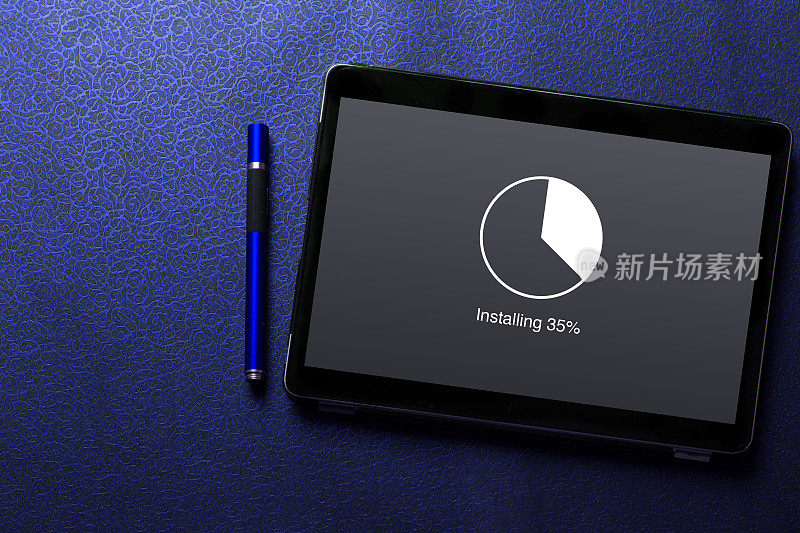 在平板电脑屏幕上安装带有循环负载百分比等待指示器概念的更新，并在蓝色图案纹理背景上使用蓝色笔