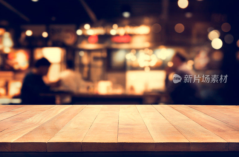 木质桌面与模糊的夜晚咖啡馆背景