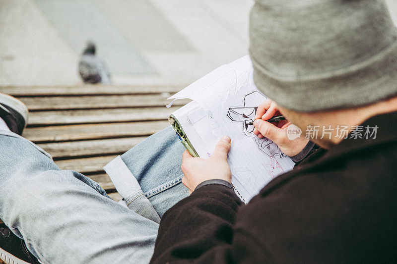 年轻的涂鸦艺术家在城市街道上素描