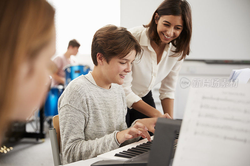 在音乐课上，男学生和老师一起弹钢琴